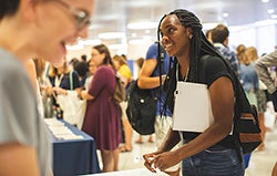 student speaking with Pitt staff at education fair