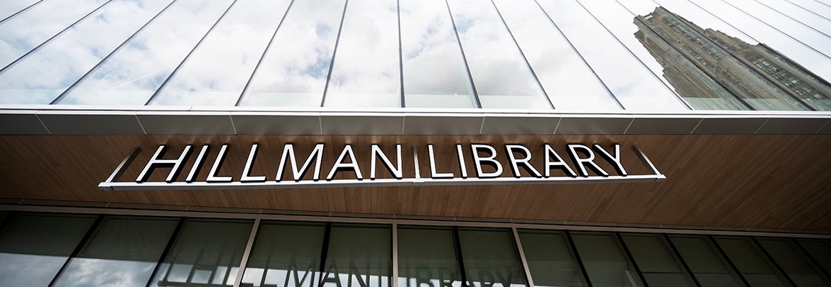 The glass front of the post-renovation Hillman LIbrary reflects the Cathedral of Learning in the window panes.