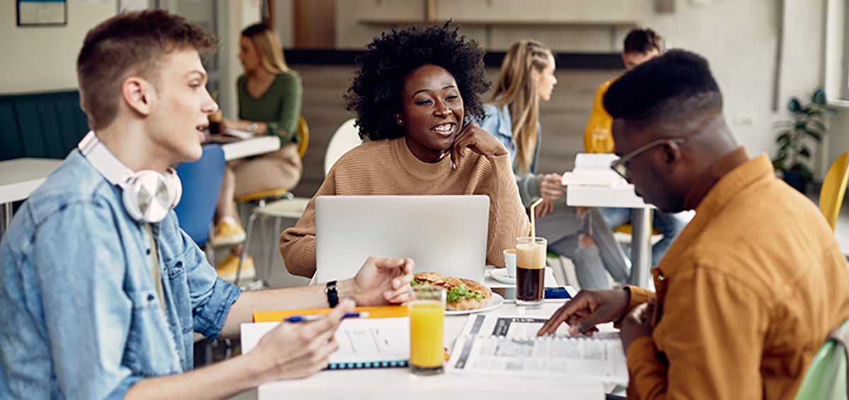 three students studying together at cafe table