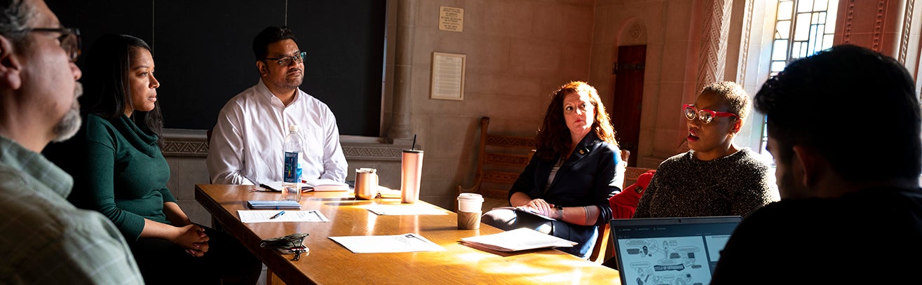 Faculty and staff meeting around a table in one of Pitt's nationality rooms