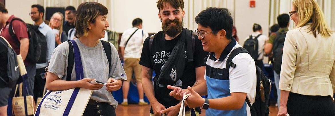 Three new Pitt grad students talk together during orientation resource fair. 