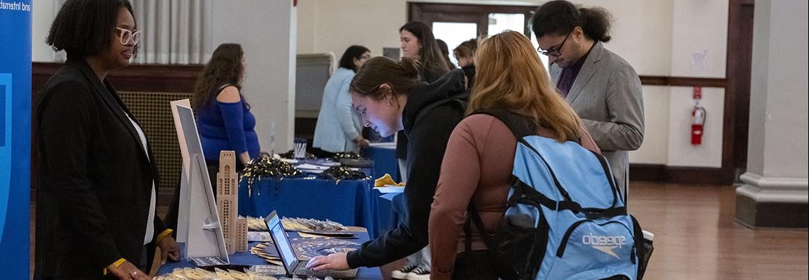 prospective grad school students visit information table during graduate and professional school fair. 