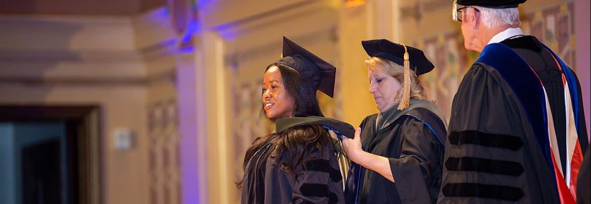 Graduating student receives graduate hood during commencement ceremony