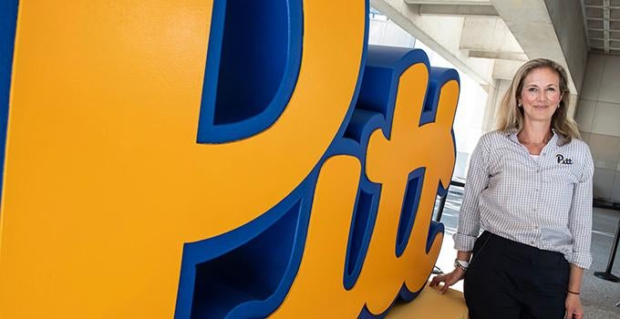 Vice Provost Amanda Godley posing with big Pitt script logo statue