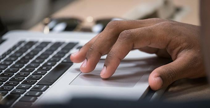 hand with fingers on trackpad of laptop keyboard