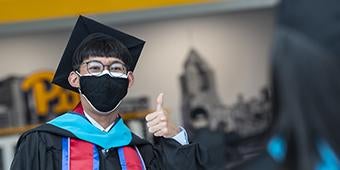 graduating student giving thumbs-up sign
