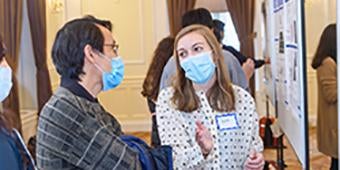 student discussing research poster at graduate biomedical symposium