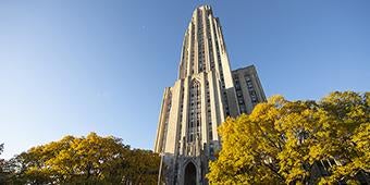 Cathedral of Learning against blue skies and behind fall foliage