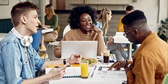 three students studying together around a table in a cafe